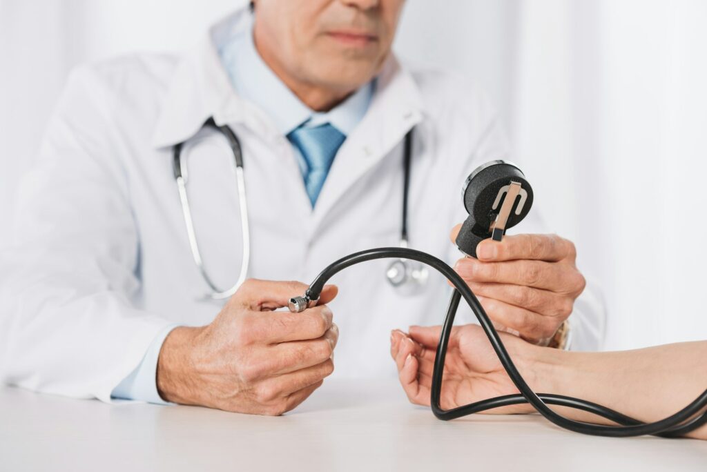 cropped image of male doctor measuring female patient pressure